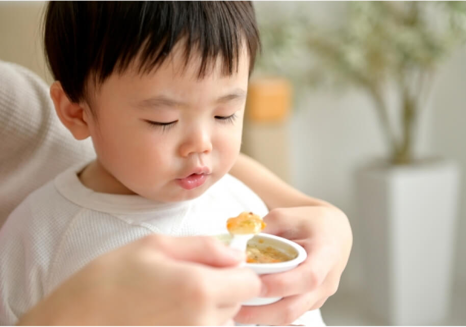離乳食を冷ましながら食べる幼児