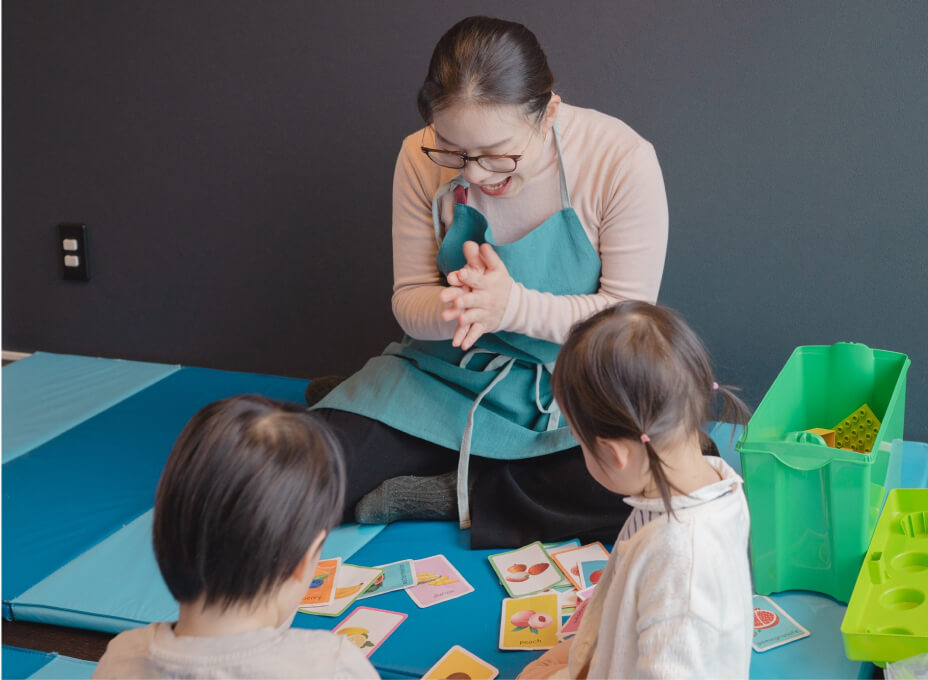 NAOMIがカード遊びを楽しむ子どもたちを見守る