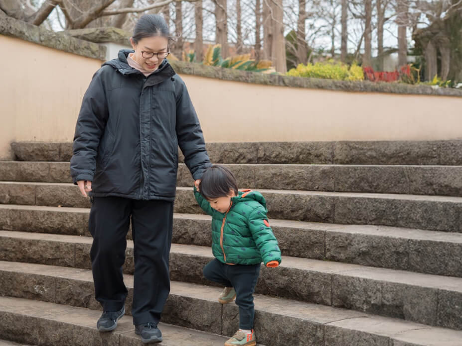 NAOMIが子どもの手を取り階段を下りる
